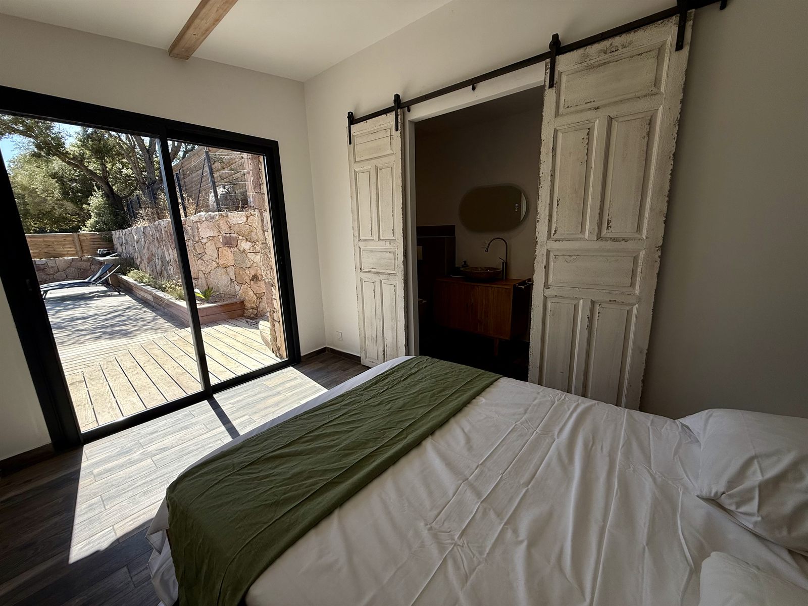 Chambre ouverte sur la terrasse en bois et le jardin — Villa Palombaggia
