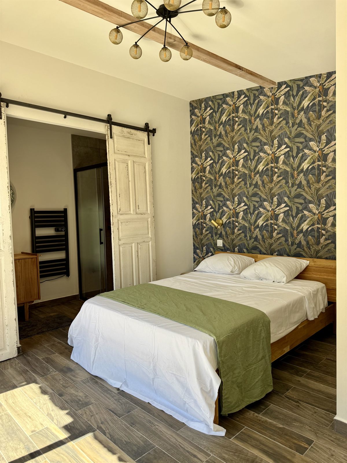 Chambre au papier peint tropical, lit double et tête de lit en bois — Villa Palombaggia