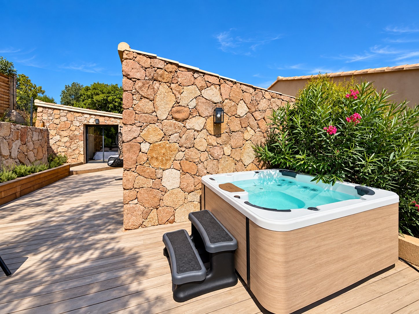 Jacuzzi privatif de la Villa Palombaggia sur sa terrasse en bois, adossé au mur de pierres sèches