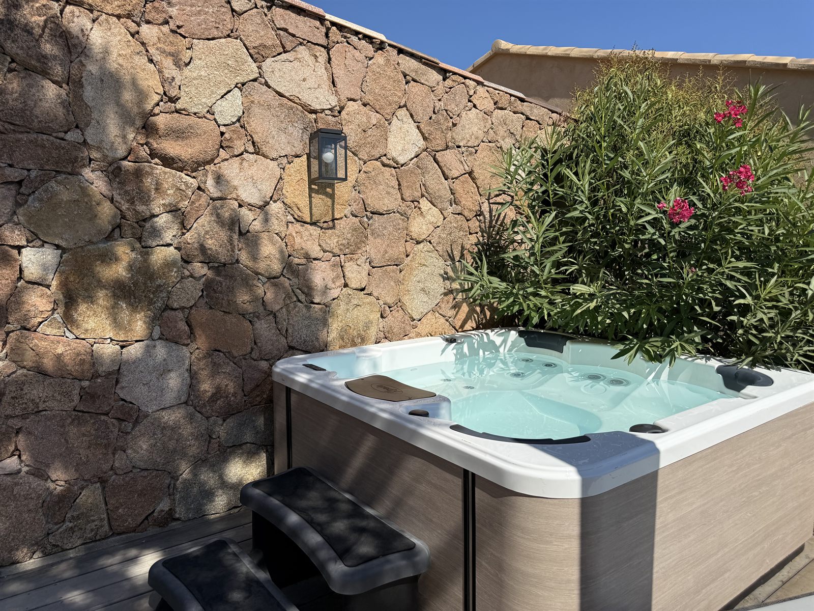 Grand jacuzzi sur la terrasse privée, adossé au mur en pierres sèches — Villa Palombaggia