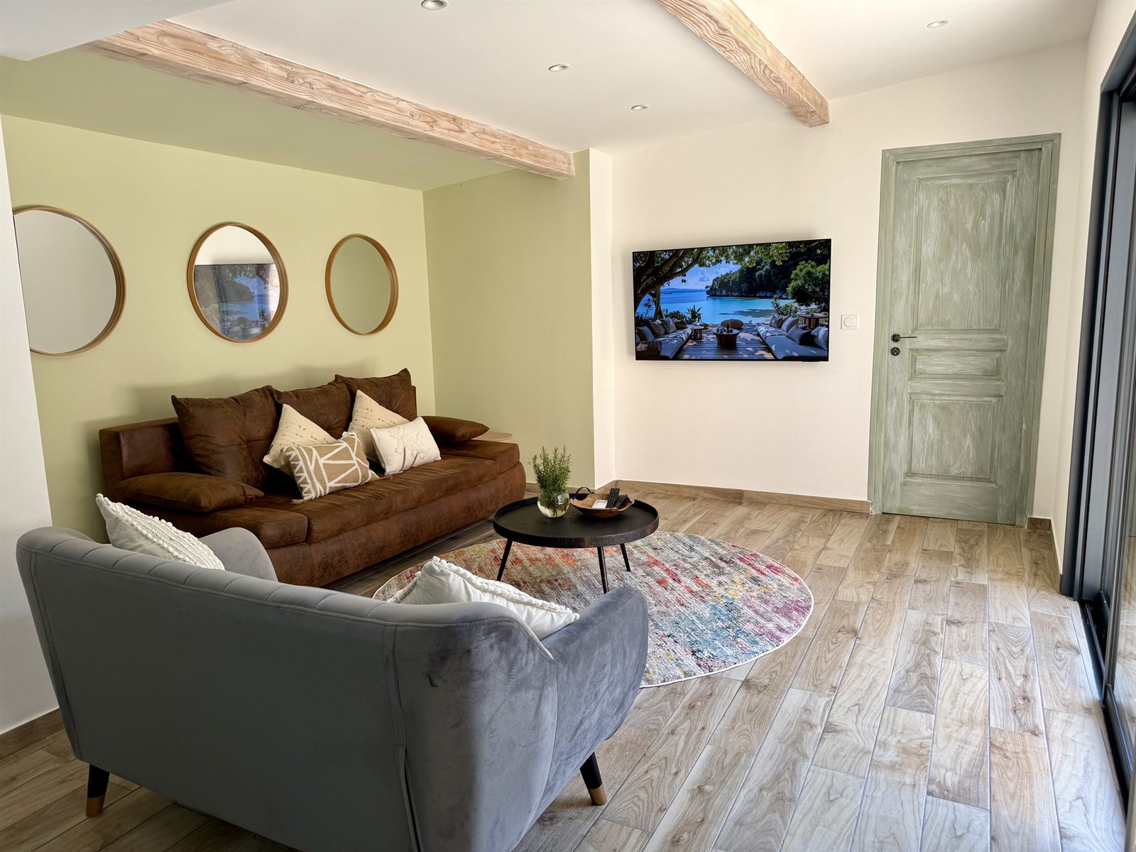 Salon lumineux avec canapé en cuir, télévision connectée et miroirs ronds — Villa Palombaggia