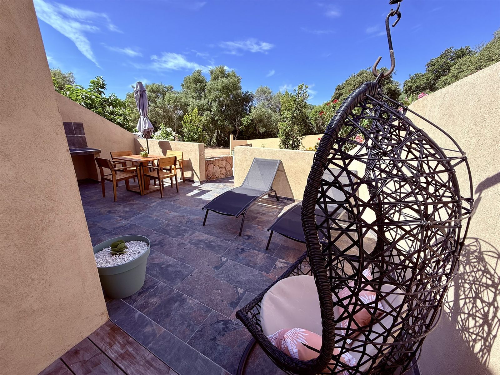 Coin détente de la terrasse — fauteuil suspendu et transats au soleil — Villa Tamaricciu